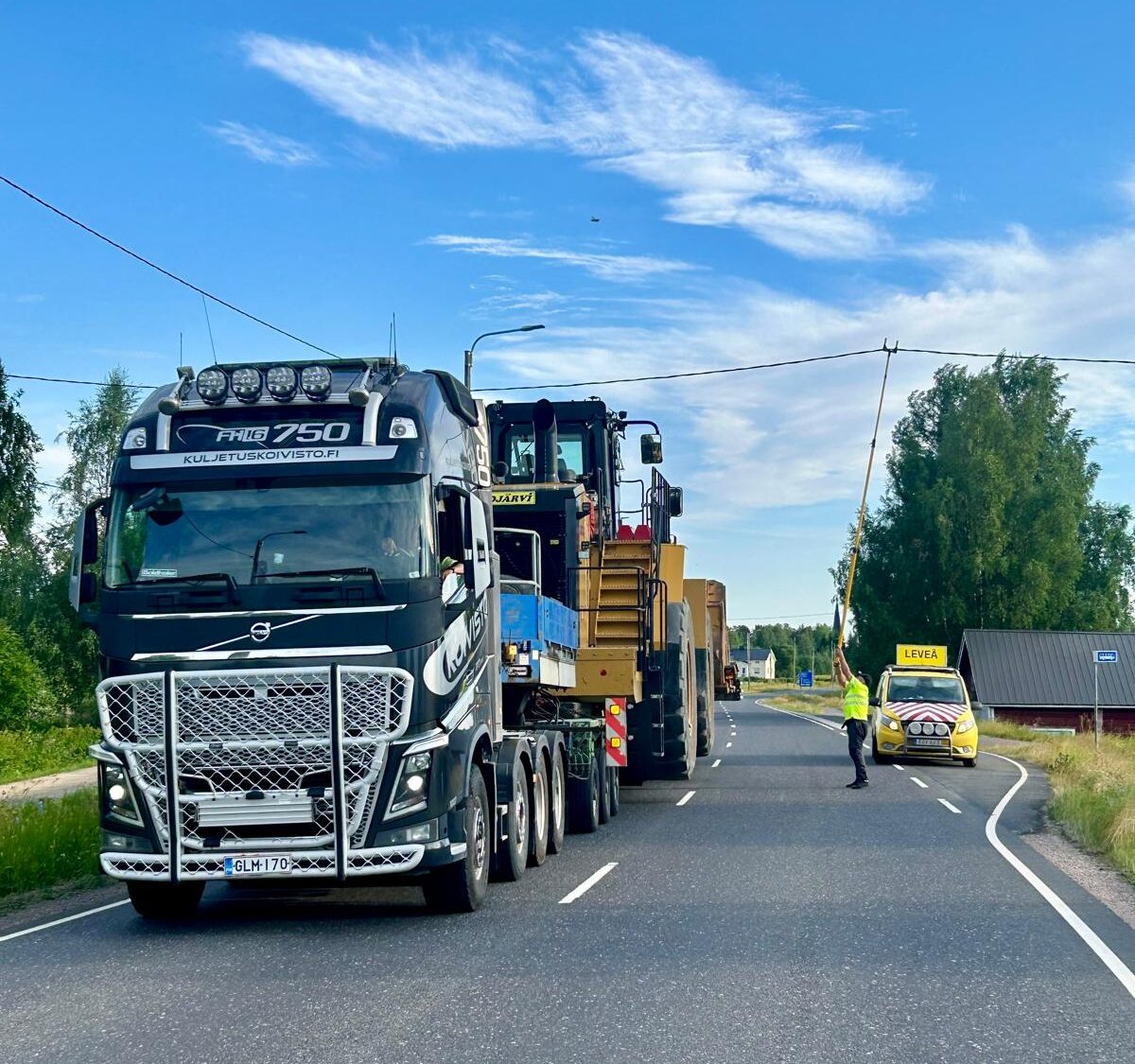 Kuljetus Koiviston erikoiskuljetus liikenteessä, raskas kuljetuskalusto ja liikenteenohjaaja turvaamassa leveän kuljetuksen etenemistä